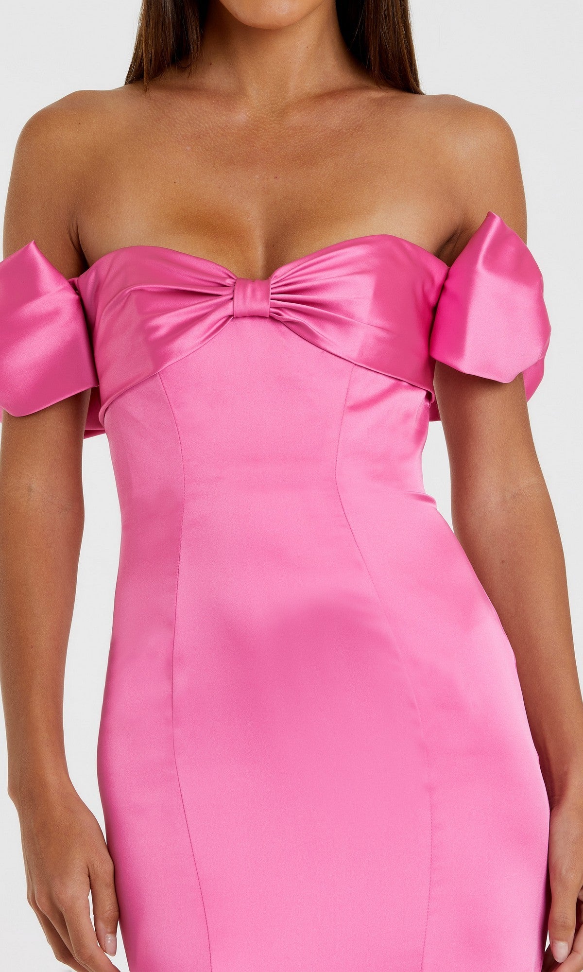 A woman wearing the Mac Duggal 68875 long formal dress—a fitted, shiny pink satin off-the-shoulder gown featuring a bow detail at the neckline.